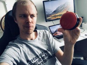 The author Hampus looking suspiciously at a red, round button in his hand